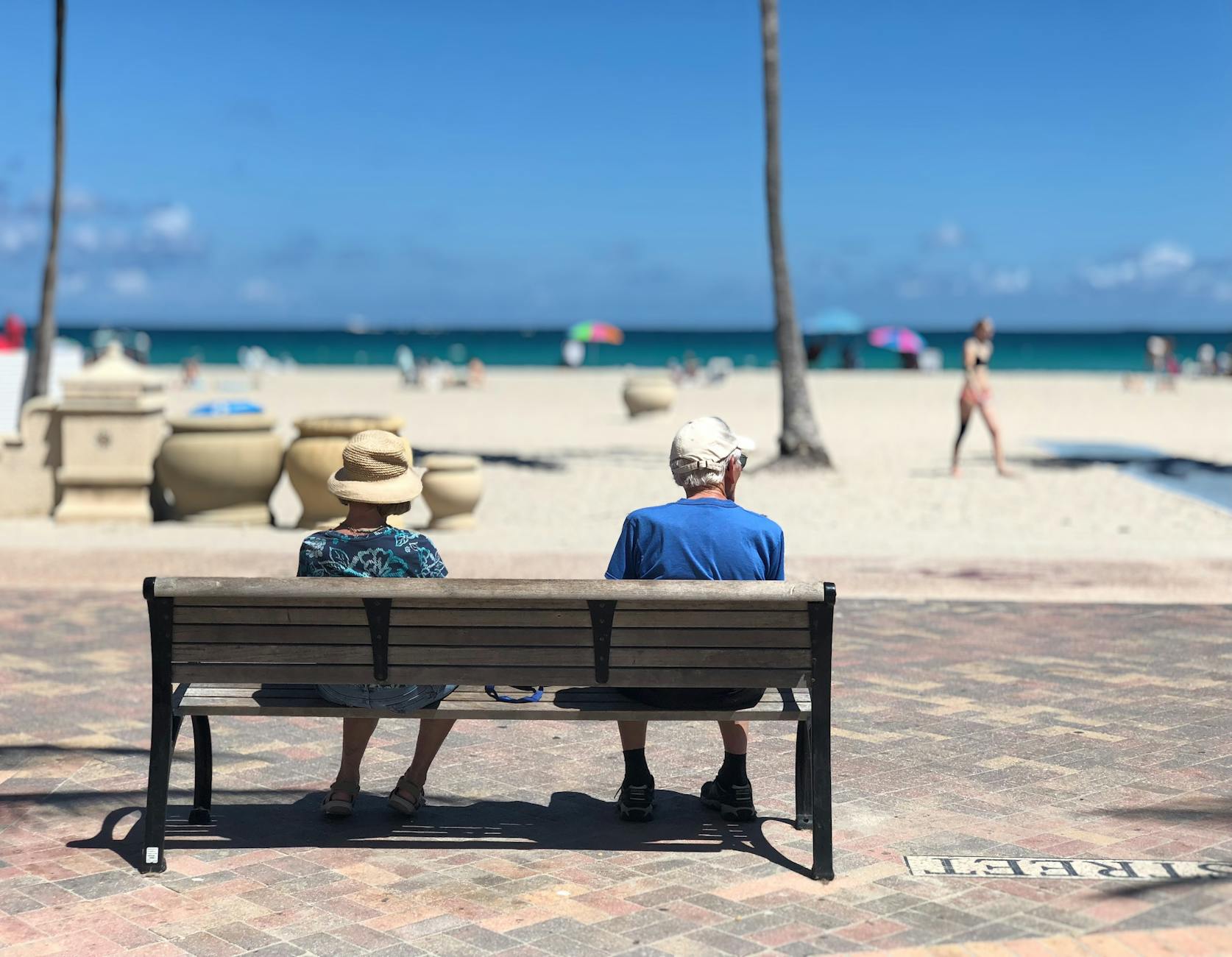 Man and woman sitting enjoying Retirement on brown wooden bench